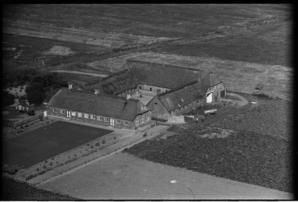 Luftfoto fra omkring 1950 af firlænget, stråtækt gård med lukket gårdsplads, omgivet af åbne marker